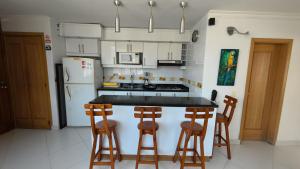 een keuken met een witte koelkast en een aanrecht met krukken bij Rivas Apartamentos Santa Marta in Santa Marta