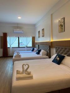 two beds in a hotel room with swans on them at SPL Betong Family Room in Betong