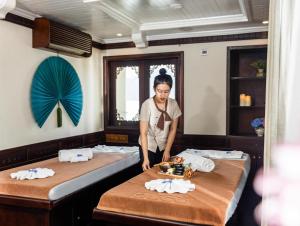una donna in piedi tra due letti in una stanza di Bhaya Luxury Halong Cruise - Manage by LuxCruises a Ha Long