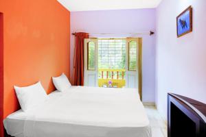 a bedroom with a white bed and an orange wall at Hotel O Mahamaya Holiday Inn in Goa +47 photos