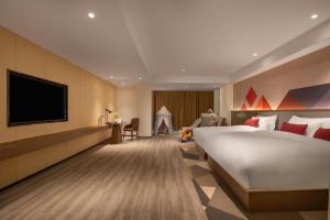 une chambre d'hôtel avec un grand lit et une télévision dans l'établissement Borrman Hotel Guilin North Railway Station Zhonghao International, à Lingchuan 224 autres photos