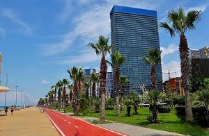 a street with palm trees and a tall building at Orbi Beach Tower in Batumi