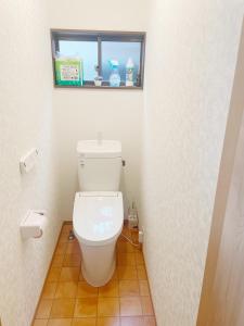 a bathroom with a white toilet with a window at Kasukabe raku house in Kasukabe