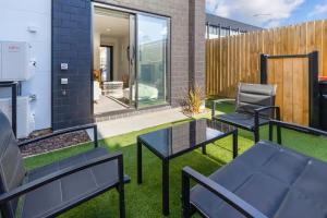 een patio met 2 zwarte stoelen en een tafel bij Stadium Suite on Southwark - Luxury in City Centre in Christchurch