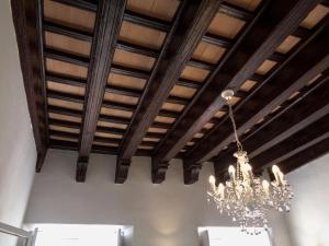 una lámpara de araña colgada de un techo con techos de madera en Casa Palacio Morla y Melgarejo, en Jerez de la Frontera