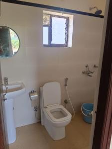 a bathroom with a toilet and a sink and a window at Udita Homestay Prayas in Shānti Niketan