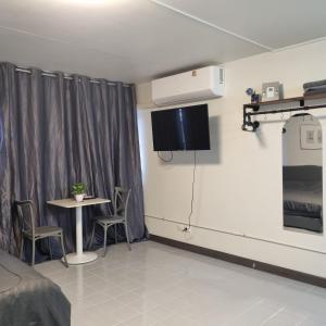 a room with a table and a tv on the wall at Popular Muang Thong Condo, Building T9, Floor 8, Room 20 in Ban Bang Phang