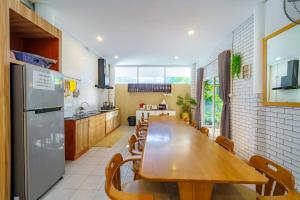 パタヤ・セントラルにあるCozy Gray Gardenの長い木製のテーブルと冷蔵庫のあるキッチン