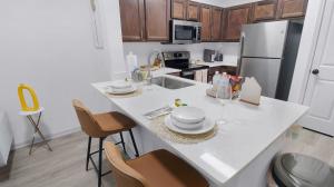 a kitchen with a counter with a sink and a refrigerator at Charming 1BD Haven I Frisco I Pool, Gym, Work Space in Frisco