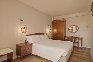 a bedroom with a large white bed and a mirror at Hotel Le Mura in Lazise