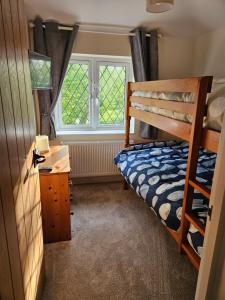 a bedroom with a bunk bed and a desk and window at Inner cottage in Brent Knoll