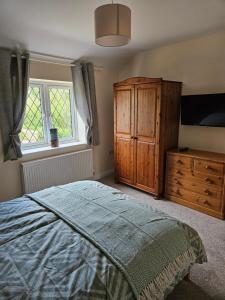 a bedroom with a bed and a dresser and a window at Inner cottage in Brent Knoll