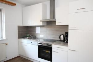 biała kuchnia z białymi szafkami i zlewem w obiekcie Ferienwohnung Wolfsberg w mieście Reutte