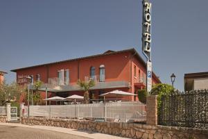 a red building with umbrellas in front of it at Hotel Le Mura in Lazise