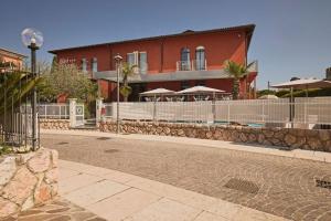 a building with a fence and a building with umbrellas at Hotel Le Mura in Lazise