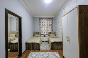a room with two beds and a table at Yodgorlik Hotel in Margilan