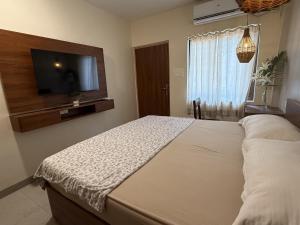 a bedroom with a bed and a flat screen tv at Casa Susegado in Panaji