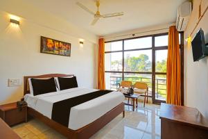 a bedroom with a bed and a large window at Townhouse Madikeri Fort Formerly Hotel Raj in Madikeri