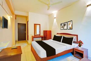 a bedroom with a bed and a desk and a television at Townhouse Madikeri Fort Formerly Hotel Raj in Madikeri