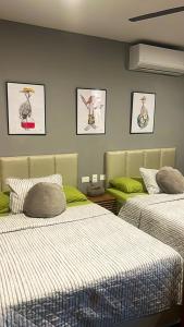 トゥルムにあるLuxury 2bdr Apt with Direct Pool in Paramar Blackのベッドが2つあり、壁に絵が2枚飾られている部屋