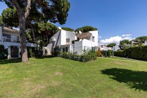 ein großes weißes Haus mit einem Baum im Hof in der Unterkunft Waves & Pines Apartment El Paraiso, Benamara in Estepona