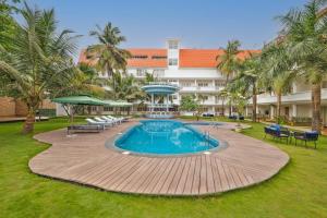 un'immagine di una piscina di un resort con tavoli e sedie di White Wharf Beach Resort Morjim Goa a Morjim