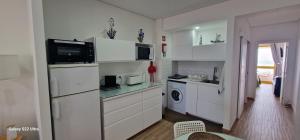a kitchen with white cabinets and a washer and dryer at Pé no mar in Monte Gordo
