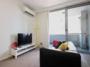 Una sala de estar con un sofá y un televisor de pantalla plana. en Super Convenient 1BR Apt Free Parking & study, en Sídney