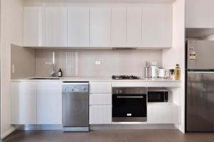 a kitchen with white cabinets and stainless steel appliances at Super Convenient 1BR Apt Free Parking & study in Sydney