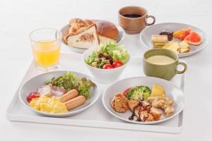a tray with four plates of food and a glass of orange juice at Via Inn Nagoya Station Tsubaki-cho in Nagoya
