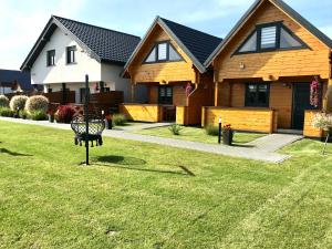 a house with a bench in the grass at Delfinek - Domki Apartamenty in Gąski