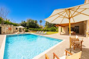 einen Pool mit einem Sonnenschirm, Stühlen und einem Tisch in der Unterkunft Villa Nafsika in Vamos