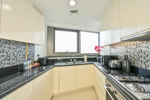 a kitchen with white cabinets and black counter tops at New Luxury 2 Bedroom with Burj Khalifa View & Spectacular Rooftop Infinity Pool Bar in Dubai