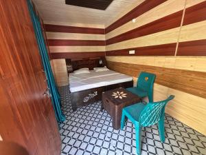 a small room with a bed and a table and chairs at Omji - Susharda Sewa Sansthan Jankichatti Near Yatra Starting Point, Yamunotri in Kharsālī