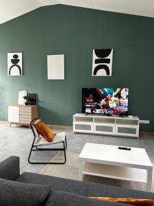 a living room with a couch and a flat screen tv at Spacious house - garden, Netflix & shops in Béguey