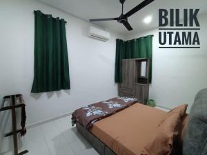 a bedroom with a bed and green curtains at Dsyaf Idaman Homestay in Jasin