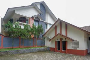 a white and red house with a tree in front of it at RedDoorz near Lokawisata Baturaden 2 in Tenjo +17 photos