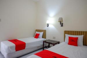 two beds with red pillows in a room at RedDoorz near Lokawisata Baturaden 2 in Tenjo