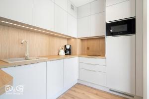 a white kitchen with white cabinets and a microwave at Apartament Zielony D&D APARTMENTS in Międzywodzie