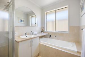 a bathroom with a tub and a sink and a mirror at Halcyon Haven in Aldinga Beach +36 photos