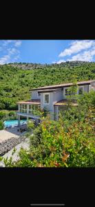 a house with a swimming pool in front of a hill at Qyteza Guest House & Camping in Shkodër