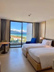 two beds in a hotel room with a view of the ocean at Oceanview apartment in The Arena Cam Ranh resort in Îlot Ba Ninh