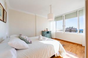 a white bedroom with a bed and a large window at Apartamento Loli in Aguadulce