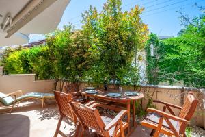 a patio with a table and chairs and trees at Kefi apartment in Pefkohori