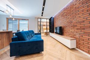 a living room with a blue couch and a brick wall at Comfort Apartments Grudziądzka in Gdańsk