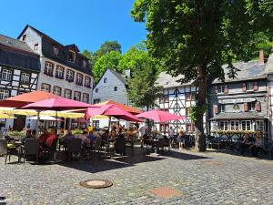 a group of people sitting at tables under umbrellas at joseph in Monschau