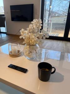 eine Vase mit Blumen und eine Fernbedienung auf dem Tisch in der Unterkunft ElbeCity Apartment in Dresden