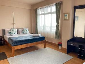 Un dormitorio con una cama y una ventana grande. en Primrose Apartment, en Darjeeling