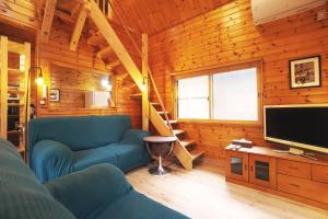 a living room with a blue couch and a television at The Creek Cottage in Habu