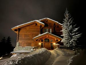 a log cabin in the snow with a christmas tree at Charme assuré in Crans-Montana +6 photos